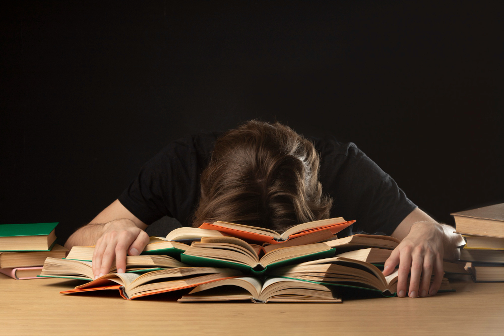 a person with their head on a pile of books