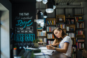 a person sitting at a table writing on a book